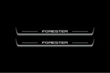 Two long door sill plates with Forester lettering and edges illuminated in white, straight-on view on a dark background.