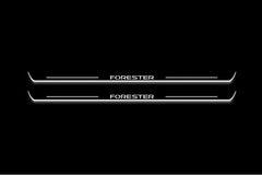Two long door sill plates with Forester lettering and edges illuminated in white, straight-on view on a dark background.
