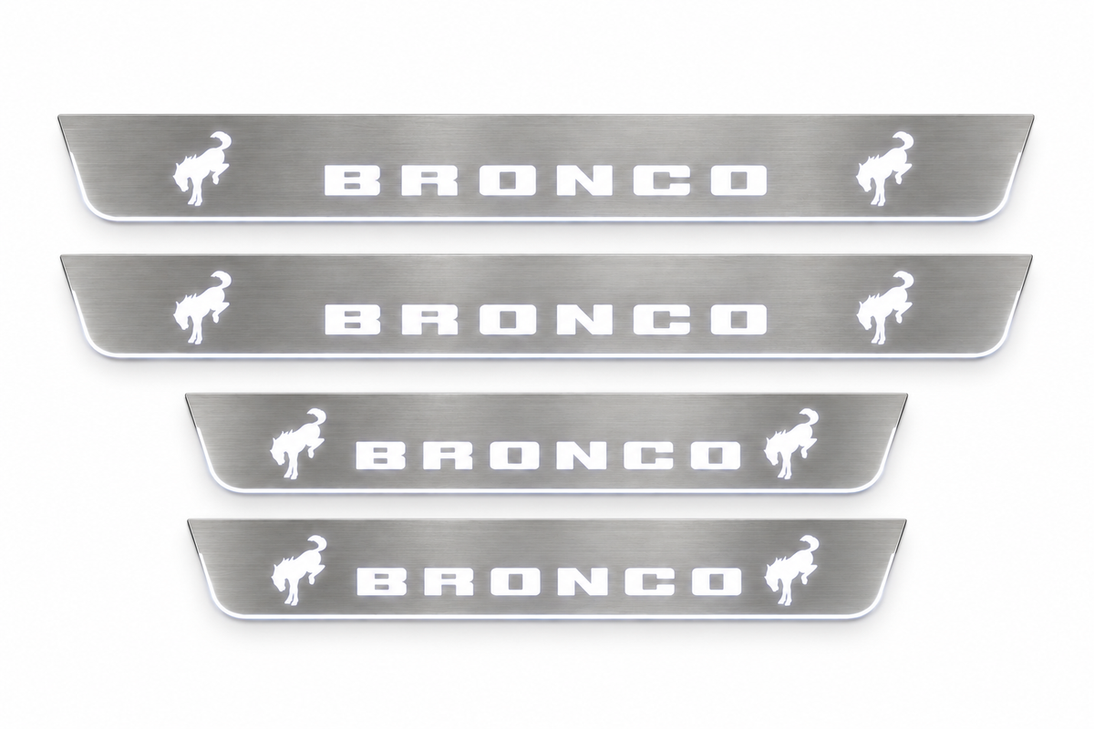 Product visualization: four Ford Bronco FRONT+REAR, two horses per plate flat brushed stainless steel door sill plates with white LED artwork and edges, white background.