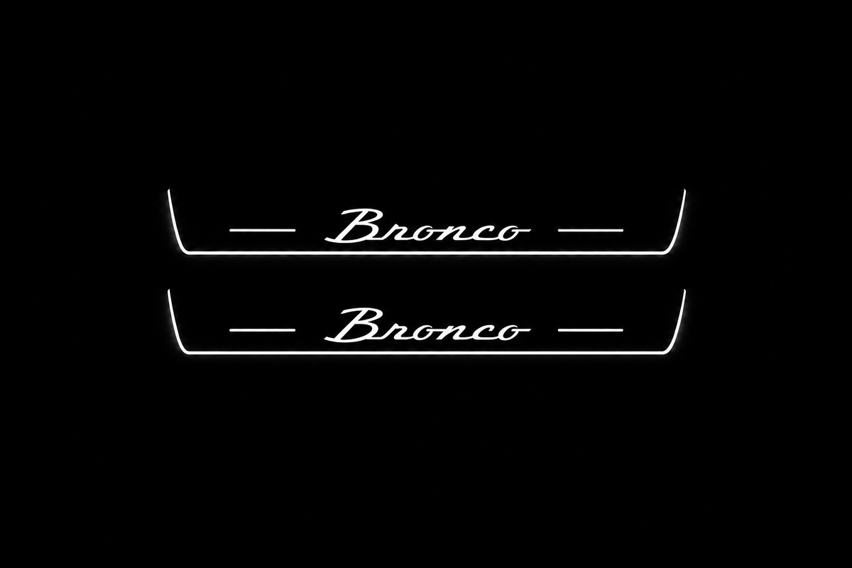 Product visualization: two exact short-proportion front plates with original Bronco script flat brushed stainless steel door sill plates with white LED artwork and edges, dark background.