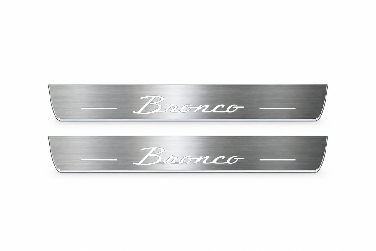 Product visualization: two exact short-proportion front plates with original Bronco script flat brushed stainless steel door sill plates with white LED artwork and edges, white background.