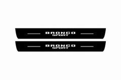 Catalogue illustration of two black Matte PRO front door sill plates with stacked illuminated BRONCO SPORT lettering on the top surface. Rear plates for FRONT+REAR are not pictured; final dimensions are selected for the vehicle during manufacture.