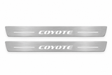 Product visualization: two flat original coyote-s197 Stainless front plates with exact artwork and white lower/end LEDs flat brushed stainless steel door sill plates with white LED artwork and edges, white background.