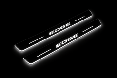 Product visualization: EDGE exact source wordmark, two flat front plates flat brushed stainless steel door sill plates with white LED artwork and edges, dark background.