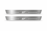 Product visualization: two Ford Edge ST FRONT flat brushed stainless steel door sill plates with white LED artwork and edges, white background.