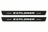 Shared catalogue illustration of two black Matte PRO front plates with italic illuminated Explorer lettering and unlit edges. The FRONT+REAR set also includes two rear plates not shown; final dimensions are selected for Ford Explorer CD6 during manufacture.