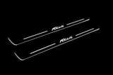 Product visualization: two exact focus-iii-script-diagonal flat Stainless front plates, own source geometry and lettering; hidden night metal, white LED zones flat brushed stainless steel door sill plates with white LED artwork and edges, dark background.