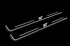 Product visualization: two exact focus-iii-st-diagonal flat Stainless front plates, own source geometry and lettering; hidden night metal, white LED zones flat brushed stainless steel door sill plates with white LED artwork and edges, dark background.