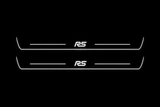 Product visualization: two Ford Focus RS front plates, exact original RS logo and bars; main metal hidden in black night lighting, white LED art and side/end edges; white secondary shows silver metal flat brushed stainless steel door sill plates with white LED artwork and edges, dark background.