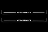 Front Pair: two front Stainless steel Fusion door sill plates with white illuminated Fusion artwork, stripes and edges on a black night background.