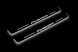 Product visualization: FUSION exact stencil, two flat source front plates flat brushed stainless steel door sill plates with white LED artwork and edges, dark background.
