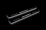 Product visualization: two exact mondeo-iv-diagonal flat Stainless front sill plates with original artwork, neutral white LEDs and own thin-edge geometry flat brushed stainless steel door sill plates with white LED artwork and edges, dark background.