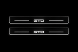 Product visualization: GTD exact source artwork, two broad flat front plates; accepted v3 proportions flat brushed stainless steel door sill plates with white LED artwork and edges, dark background.