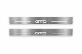 Product visualization: GTD exact source artwork, two broad flat front plates; accepted v3 proportions flat brushed stainless steel door sill plates with white LED artwork and edges, white background.