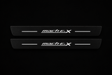 Catalogue illustration of two black Matte PRO front door sill plates with stylized white mach E 4 X lettering and thin horizontal lines illuminated only on top. Rear plates for FRONT+REAR are not pictured; dimensions are selected for the vehicle during manufacture.