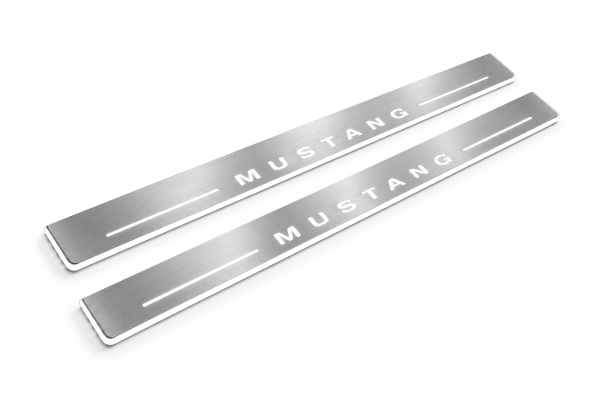 Product visualization: MUSTANG spaced letters, two flat source front plates flat brushed stainless steel door sill plates with white LED artwork and edges, white background.