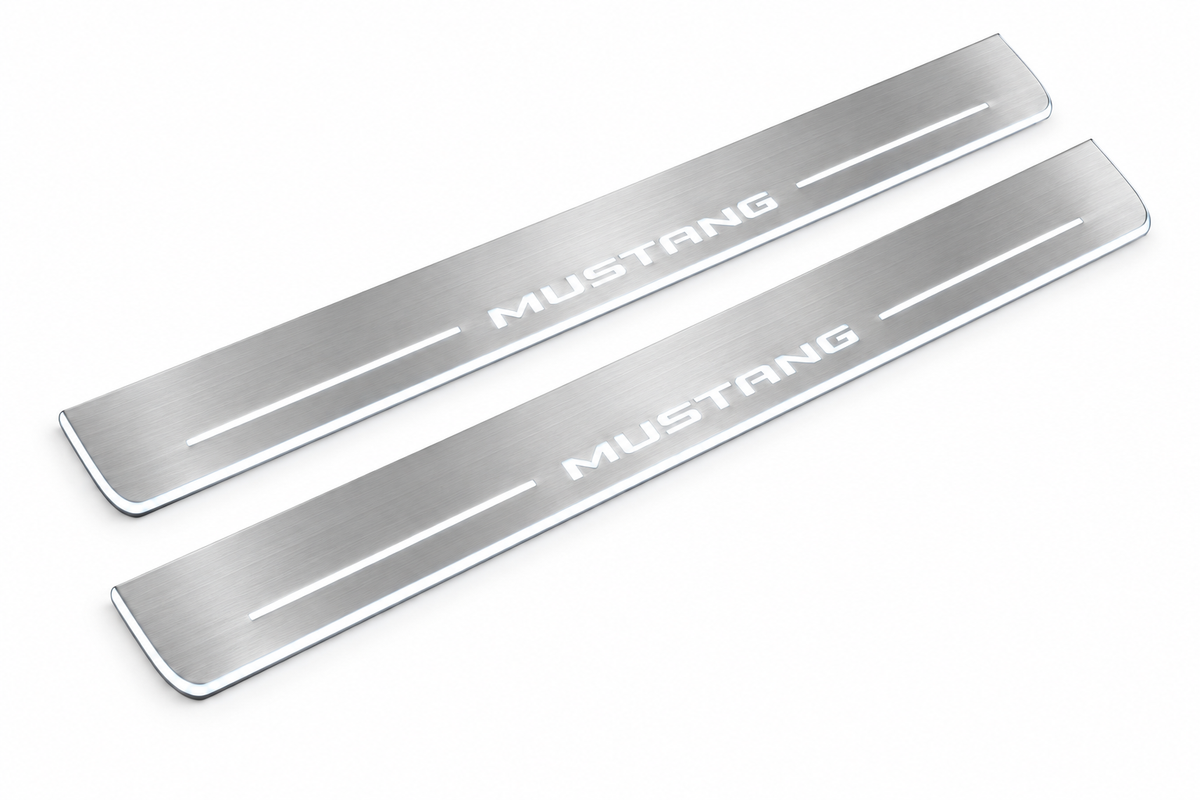Product visualization: MUSTANG compact block lettering, two flat source front plates flat brushed stainless steel door sill plates with white LED artwork and edges, white background.