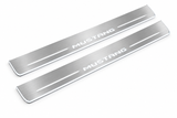 Product visualization: MUSTANG compact block lettering, two flat source front plates flat brushed stainless steel door sill plates with white LED artwork and edges, white background.