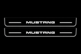 Product visualization: two flat mustang-simple-bars Stainless front plates with original source lettering and white LED zones flat brushed stainless steel door sill plates with white LED artwork and edges, dark background.