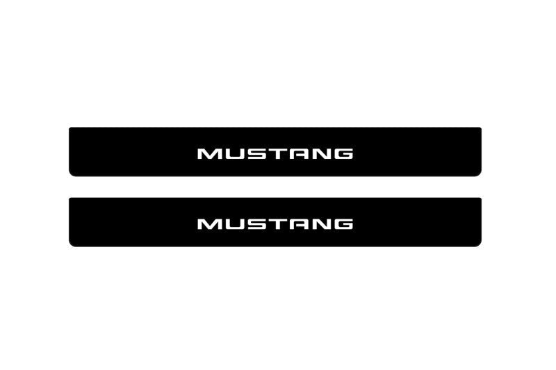 Catalog illustration of two black front door sill plates with Mustang lettering.