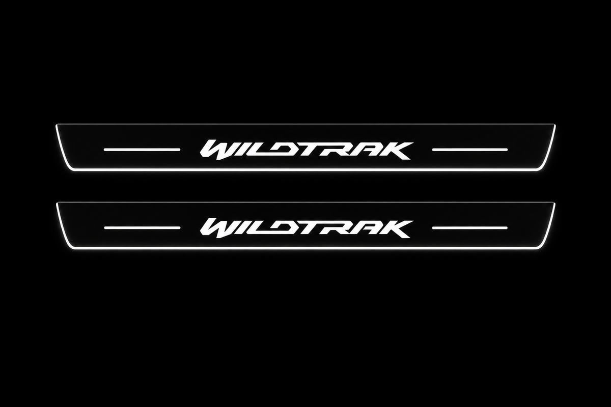 Product visualization: two flat front plates with original italic WILDTRAK logo and side bars flat brushed stainless steel door sill plates with white LED artwork and edges, dark background.