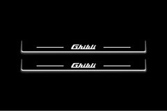 Two long door sill plates with Ghibli lettering and edges illuminated in white, straight-on view on a dark background.