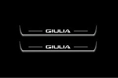 Two short door sill plates with Giulia lettering and edges illuminated in white, straight-on view on a dark background.