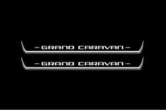 Two long door sill plates with Grand Caravan lettering and edges illuminated in white, straight-on view on a dark background.