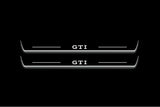 Two long door sill plates with GTI lettering and edges illuminated in white, straight-on view on a dark background.