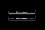 Two long door sill plates with Hennessey lettering and edges illuminated in white, straight-on view on a dark background.