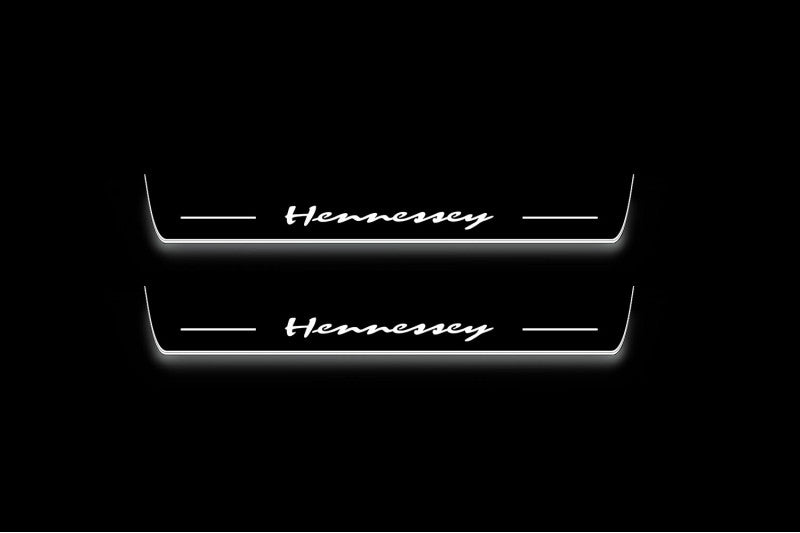 Two long door sill plates with Hennessey lettering and edges illuminated in white, straight-on view on a dark background.