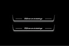Two long door sill plates with Hennessey lettering and edges illuminated in white, straight-on view on a dark background.