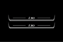 Two long door sill plates with i30 lettering and edges illuminated in white, straight-on view on a dark background.