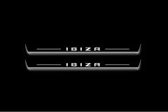Two long door sill plates with Ibiza in block lettering lettering and edges illuminated in white, straight-on view on a dark background.