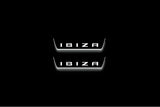 Two short door sill plates with Ibiza in block lettering lettering and edges illuminated in white, straight-on view on a dark background.