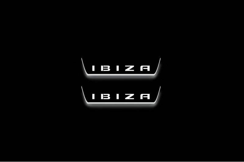 Two short door sill plates with Ibiza in block lettering lettering and edges illuminated in white, straight-on view on a dark background.