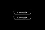 Two short door sill plates with Impreza lettering and edges illuminated in white, straight-on view on a dark background.