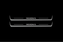 Two long door sill plates with Insignia lettering and edges illuminated in white, straight-on view on a dark background.