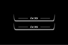 Two long door sill plates with ix35 lettering and edges illuminated in white, straight-on view on a dark background.