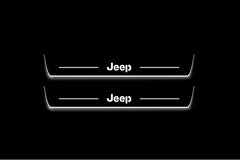 Two long door sill plates with Jeep lettering and edges illuminated in white, straight-on view on a dark background.