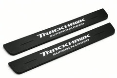 Catalogue illustration of two front black Matte PRO LED door sill plates with illuminated TrackHawk Supercharged lettering for Jeep Grand Cherokee WK2; dimensions are selected during manufacture.