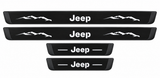Catalogue illustration of two long black Matte PRO front sill plates with Jeep lettering and mountain graphics, plus two shorter rear plates with Jeep lettering and lines. White top lettering illuminated; side edges unlit. Vehicle-specific dimensions are not depicted. FRONT option includes front plates only.