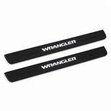 Catalogue illustration of two black Matte PRO front door sill plates with white WRANGLER lettering illuminated only on top. Edges are unlit; rear plates for FRONT+REAR are not pictured. Final dimensions are selected for Wrangler JL during manufacture.