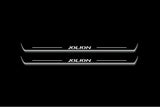 Two long door sill plates with Jolion lettering and edges illuminated in white, straight-on view on a dark background.