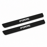 Catalogue illustration of two black Matte PRO front door sill plates with stylised illuminated FORTE lettering on the top surface. Edges are unlit; rear plates for FRONT+REAR are not pictured. Final dimensions are selected for Kia Forte Sedan YD during manufacture.