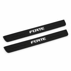 Catalogue illustration of two black Matte PRO front door sill plates with stylised illuminated FORTE lettering on the top surface. Edges are unlit; rear plates for FRONT+REAR are not pictured. Final dimensions are selected for Kia Forte Sedan YD during manufacture.