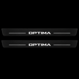 Catalogue illustration of two black Matte PRO front door sill plates with illuminated OPTIMA lettering and short lines on the top surface. Rear plates are not pictured; final dimensions are selected for the vehicle.