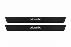 Catalogue illustration of two black Matte PRO front door sill plates with illuminated lowercase picanto lettering on top. Edges remain unlit. Rear plates for a FRONT+REAR set are not shown; final dimensions are chosen for the Kia Picanto JA during manufacture.