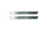 Two short silver-finished door sill plates with Kodiaq lettering on a light background, straight-on view.