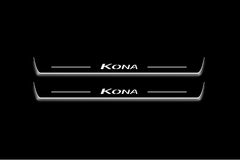 Two long door sill plates with Kona lettering and edges illuminated in white, straight-on view on a dark background.